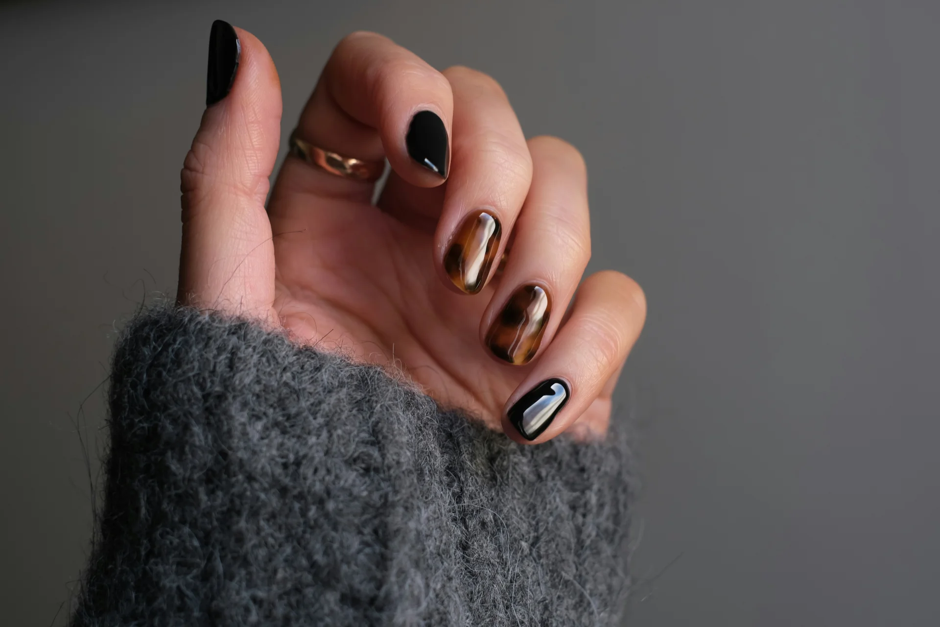 Zbliżenie na dłoń kobiety noszącej srebrny pierścionek i czarny manicure.