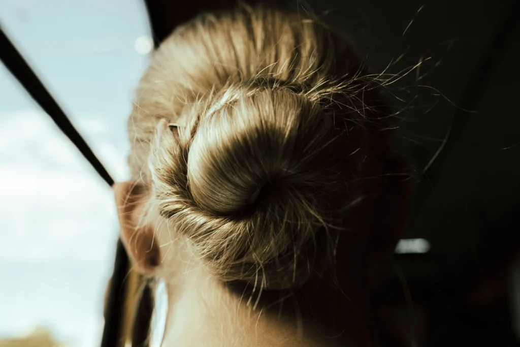 Zbliżenie na blond kok włosów, oświetlony promieniami słońca, w eleganckim stylu.