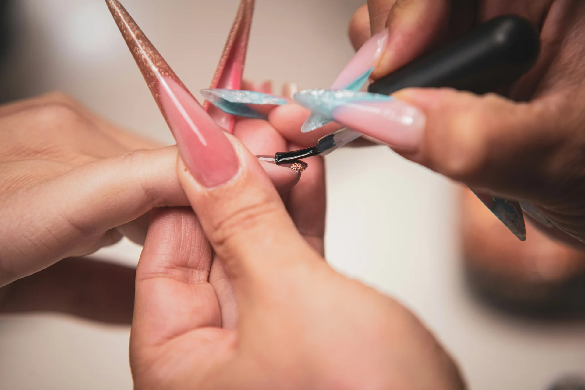 Manicurzystka precyzyjnie maluje długie, sztuczne paznokcie, tworząc idealny manicure.